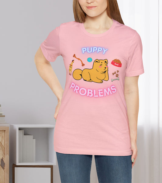 Puppy Problems tee in pink. Picture of an overwhelmed dog lying on its belly with toys and food around surrounding it.